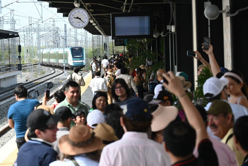 Viajeros esperan en el andén mientras se aproxima una unidad del Tren Maya.