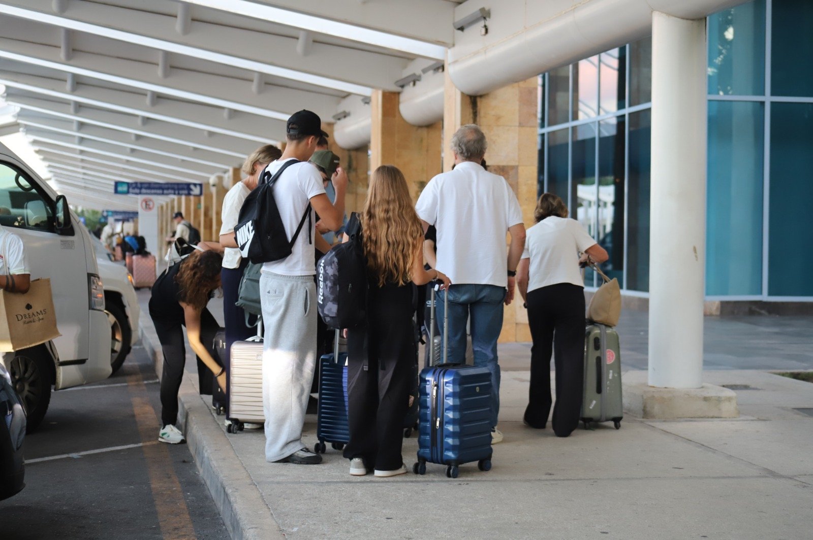 Viajeros con equipaje en el exterior de la terminal aérea de Cancún.